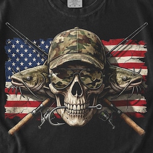 Puede incluir: Camiseta negra con una calavera que lleva gafas de sol y una gorra de camuflaje, con dos bagres y cañas de pescar cruzadas detrás. Un diseño de la bandera estadounidense está en el fondo, con las estrellas y las rayas visibles.