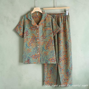 May include: A two-piece pajama set with a floral pattern in shades of green, orange, and blue. The short-sleeved top has a button-down front and a notched collar. The pants are long and have a matching floral design. The text "layla night wear for restful night" is at the bottom.