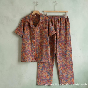 May include: A two-piece pajama set with a floral pattern in shades of red, orange, and blue. The short-sleeved button-down shirt has a chest pocket and orange trim. The matching pants have an elastic waistband. The text "layla night wear for restful night" is at the bottom.