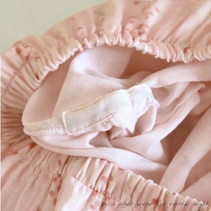 May include: Close-up of light pink sleepwear with an elastic waistband and a soft, flowing fabric. The fabric has a subtle pattern of small, darker pink dots. The text "layla night wear for restful night" is visible at the bottom.