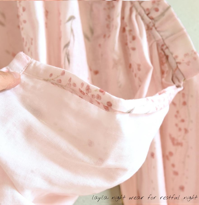 May include: Close-up of a light pink pajama top with a floral pattern. The inside of the sleeve is visible, showing a contrasting floral print. The text "layla night wear for restful night" is at the bottom.