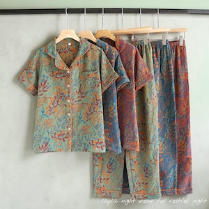 May include: A collection of floral-patterned pajama sets in shades of green, blue, and purple, hanging on wooden hangers. Each set includes a short-sleeved button-up shirt and matching pants. The text "layla night wear for restful night" is visible at the bottom.