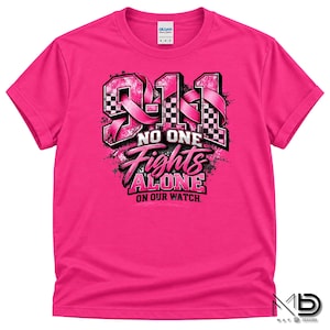 Könnte beinhalten: Ein leuchtend pinkfarbenes Kurzarm-T-Shirt mit einem Grafikdesign und dem Text 9-1-1 NO ONE FIGHTS ALONE ON OUR WATCH. Das Design enthält ein rosa Band, schwarz-weiße Karomuster und abgenutzte schwarze Tintentexturen.