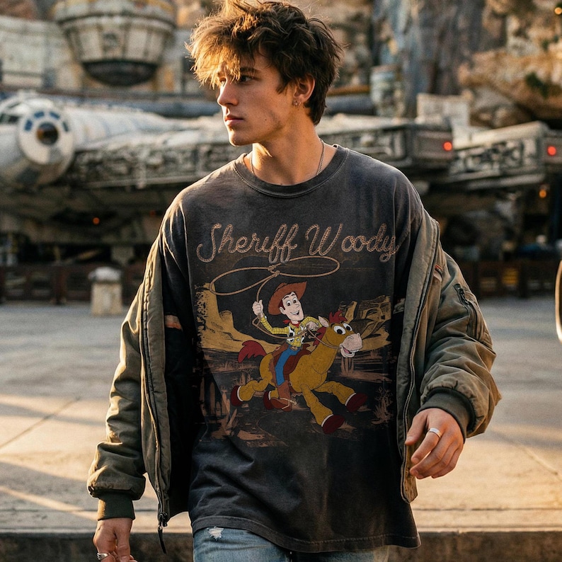 K&ouml;nnte beinhalten: Dunkelgraues Langarm-T-Shirt mit Sheriff Woody und Pferde-Grafik. Die Grafik zeigt Woody, der mit einem Lasso auf einem Pferd reitet. Das Shirt hat einen Vintage-Look.
