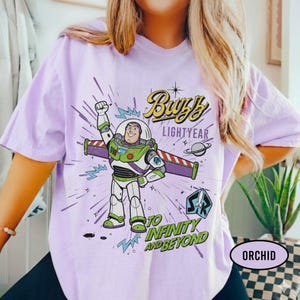 May include: A white ceramic mug with a black handle and the text "But First, Coffee" in a bold, black font. The mug is set against a blurred background, suggesting a cozy setting.