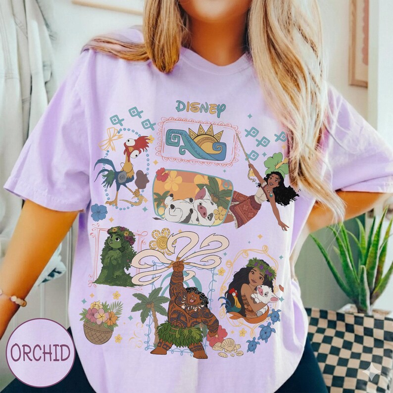 以下が含まれることがあります： 映画モアナのディズニーキャラクターが描かれた、薄紫色のTシャツ。モアナ、マウイ、ヘイヘイ、プアなど、キャラクターのカラフルなイラストが描かれています。「DISNEY」の文字が上部にプリントされています。