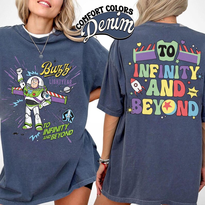 Op de afbeelding: Denimblauwe t-shirt met Buzz Lightyear uit Toy Story. De voorkant heeft Buzz in zijn ruimtepak met de woorden "Buzz Lightyear" en "To Infinity and Beyond". De achterkant van de shirt heeft de zin "To Infinity and Beyond" in kleurrijke letters.