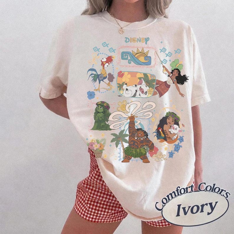 以下が含まれることがあります： ディズニーのキャラクターが描かれたアイボリー色のTシャツ。クルーネックと半袖です。グラフィックにはキャラクターのイラストと上部に「Disney」の文字が含まれています。Tシャツには「Comfort Colors Ivory」と表示されています。