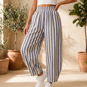 K&ouml;nnte beinhalten: Hoch taillierte Hose mit vertikalem blau-wei&szlig;em Streifenmuster. Die Hose hat eine weite Beinform, einen gerafften elastischen Bund und eine lockere Passform, die bis zu den Kn&ouml;cheln reicht, kombiniert mit einem schlichten wei&szlig;en bauchfreien Oberteil.