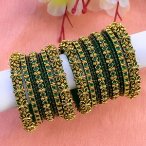 May include: A set of gold-toned bangles featuring deep green square-cut stones and intricate floral metalwork. The bracelets are arranged in a row, showcasing alternating bands of solid green and ornate gold patterns with small metallic beads.