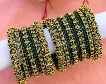 May include: A set of gold-toned bangles featuring deep green square-cut stones and intricate floral metalwork. The bracelets are arranged in a row, showcasing alternating bands of solid green and ornate gold patterns with small metallic beads.