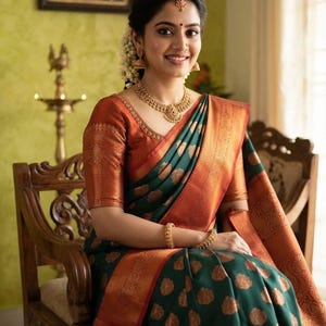 May include: A dark green silk saree featuring a wide copper-toned border with intricate woven patterns and matching copper-toned floral motifs throughout the fabric, paired with a coordinating copper-toned blouse and gold jewelry.