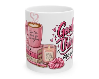May include: A white ceramic mug featuring a pink coffee cup with the text Dear God, thank you for everything, a stack of books labeled PRAY, DREAM, MANIFEST, a candle labeled Take it one day at a time, a pink pen, a scrunchie, and Good Things are coming.