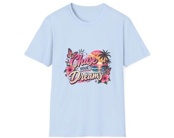 May include: A light blue short-sleeve t-shirt featuring a graphic print of a sunset over the ocean with palm trees, hibiscus flowers, butterflies, and a crown. The text "Chase your Dreams" is printed in a stylized pink and white font.