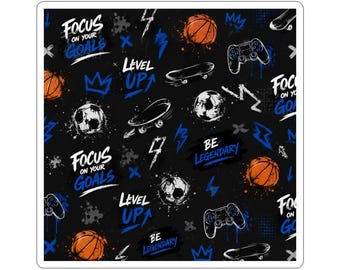 May include: A square sticker featuring a black background with a repeating pattern of orange basketballs, white soccer balls, black skateboards, and black game controllers. The design includes blue and white text reading Focus On Your Goals, Level Up, and Be Legendary, along with blue lightning bolts and crown icons.