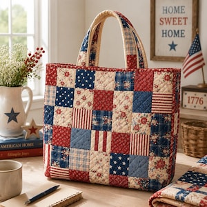 May include: A quilted tote bag featuring a patchwork design of red, white, and blue fabric squares. The pattern includes floral prints, stars, and stripes. The bag has two matching quilted handles and a rectangular shape with stitched detailing.