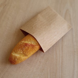 May include: A brown paper bag with a crusty baguette inside.