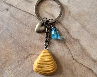 Handmade sfogliatella keychain in golden polymer clay with blue crystal and bronze heart, inspired by Neapolitan tradition