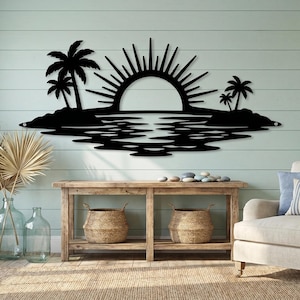 May include: A black metal wall art piece featuring a tropical island scene with a rising sun, palm trees on both sides, and a reflective water pattern below. The design is a flat, silhouette-style cutout mounted horizontally on a wall surface.