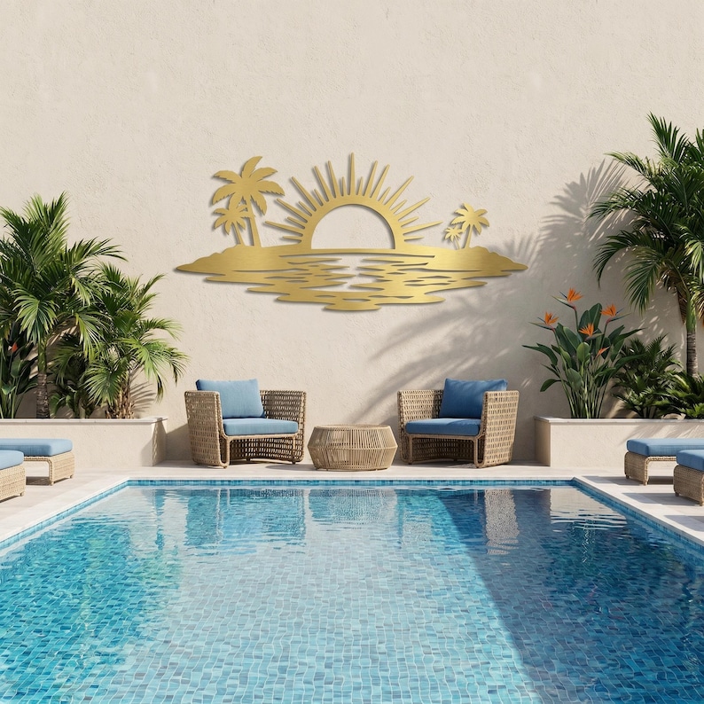 May include: A gold-colored metal wall art piece featuring a stylized tropical scene with a rising sun, palm trees, and water reflections. The design is mounted on a wall above two wicker chairs and a small table, positioned near a swimming pool.