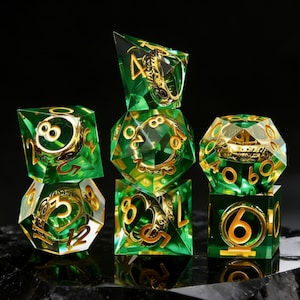 Puede incluir: Un conjunto de siete dados poliédricos verdes y dorados para juegos de mesa. Cada dado tiene un cuerpo verde transparente con números dorados y diseños intrincados. Los dados están dispuestos sobre una superficie oscura.