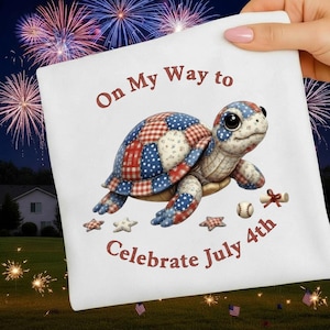 May include: White square pillow with a patriotic turtle design. The turtle's shell is patterned with red, white, and blue stars and stripes. Text reads "On My Way to Celebrate July 4th". Fireworks and stars are in the background.