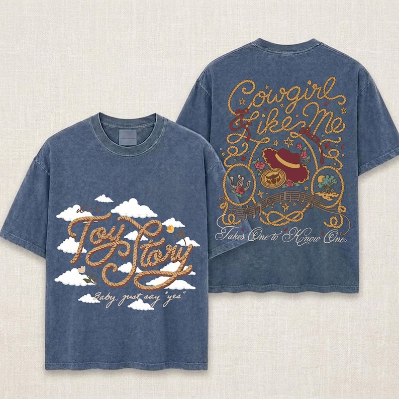 以下が含まれることがあります： ブルーのケミカルウォッシュ加工Tシャツ。前面には白い雲と「Toy Story Baby, just say yes」の文字がプリントされています。背面にはロープ風のデザインと「Cowgirl Like Me Takes One to Know One」の文字、およびウエスタン調のイラストが描かれています。
