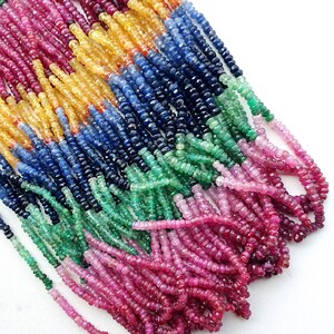 Könnte beinhalten: Mehrere Stränge aus kleinen, facettierten Edelsteinperlen, die in einem lebendigen Regenbogenverlauf angeordnet sind. Die Perlen wechseln zwischen Schattierungen von tiefem Pink, hellem Gelb, Dunkelblau und Smaragdgrün und bilden ein buntes Arrangement.