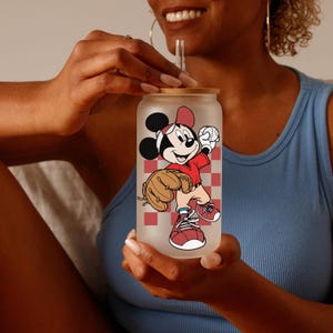 May include: Frosted glass can-shaped tumbler with a bamboo lid and a clear straw. The tumbler features a cartoon image of Mickey Mouse in a baseball uniform, set against a red and white checkered background.