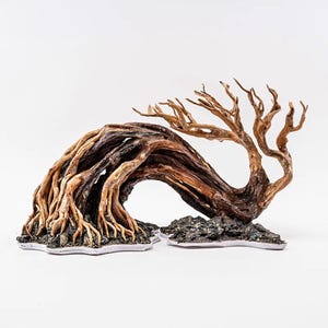 May include: A decorative aquarium driftwood sculpture. The natural wood has a curved, arching design with exposed roots and branches. The driftwood is mounted on a small, rocky base, and is a mix of light and dark brown colors.