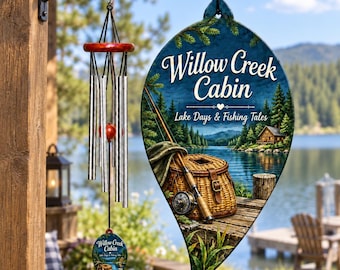 Könnte beinhalten: Ein Windspiel mit silbernen Metallröhren, einem roten Holzoberteil und einem blattförmigen Schild mit der Aufschrift Willow Creek Cabin, Lake Days & Fishing Tales, einer Seenlandschaft, einer Angelrute und einem Weidenkorb sowie einem kleinen Anhänger.