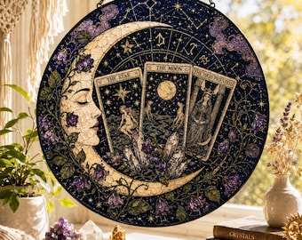 May include: Round stained glass panel featuring a crescent moon, floral accents, and three tarot cards: The Star, The Moon, and The High Priestess. The panel is predominantly navy blue with gold and purple details, and is suspended by a chain.