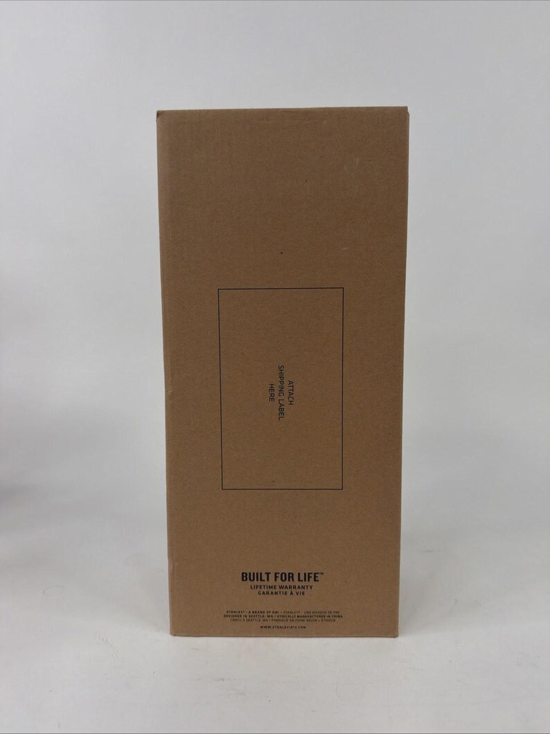K&ouml;nnte beinhalten: Ein rechteckiger Versandkarton aus brauner Pappe mit einem schwarzen Rechteck in der Mitte, das den Text ATTACH SHIPPING LABEL HERE enth&auml;lt. Unten befindet sich der Text BUILT FOR LIFE LIFETIME WARRANTY und weitere kleine Schrift.