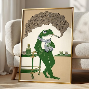 May include: A framed art print featuring a green frog wearing a patterned scarf and trousers, leaning against a bar cart. The frog holds a cigar with smoke swirling above. The background is a solid tan colour with a green bar cart and glasses.