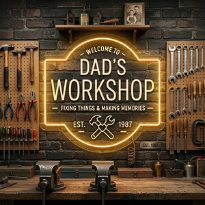 May include: A workshop scene with tools and a neon sign that reads "Welcome to Dad's Workshop". The sign also says "Fixing Things & Making Memories" and "Est. 1987". Tools are organized on pegboards, and there are vises on a wooden workbench.