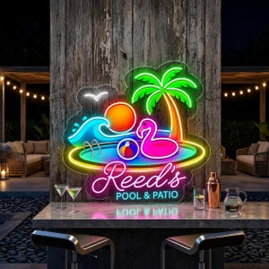May include: A neon sign with a tropical pool scene, featuring a flamingo, palm tree, and a beach ball. The sign reads "Reed's Pool & Patio" in a cursive font, with a vibrant color scheme of blue, pink, and green.