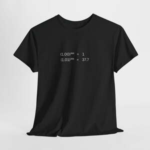 May include: Black t-shirt with white text. The text displays two mathematical equations: (1.00)^365 = 1 and (1.01)^365 = 37.7. The shirt is made of a soft material and has short sleeves.