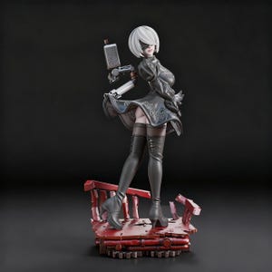 May include: A detailed figurine of a character from the game NieR:Automata. The figure is in a black dress, black boots, and a white bob haircut. The figure is holding a weapon and standing on a red platform.