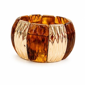 Peut inclure: Un large bracelet segmenté avec des sections alternées de matériaux ambrés et dorés. Les sections ambrées ont un aspect texturé et facetté, tandis que les sections dorées présentent un motif texturé en forme de feuille. Le bracelet est conçu pour être porté au poignet.