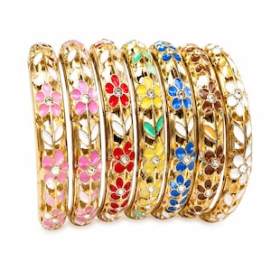 Op de afbeelding: Een set van zeven goudkleurige metalen armbanden met een opengewerkt rankontwerp met kleurrijke emaille bloemen en bladeren. Elk bloemhart is geaccentueerd met een kleine heldere strass-steen. De armbanden zijn roze, rood, geel, blauw, bruin en wit.