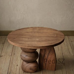 Può includere: Un tavolino rotondo in legno dal design unico. Il tavolo presenta un piano circolare sostenuto da una base sferica impilata e una gamba in legno massello intagliato. Il tavolo è realizzato in legno dai toni medi caldi e ha il testo "PediSZ" intagliato.