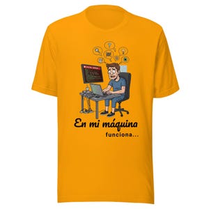 Può includere: T-shirt giallo senape con un cartone animato di una persona davanti a un computer che mostra un messaggio di errore. Il testo sulla maglietta recita "En mi máquina funciona..."