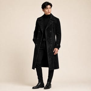 May include: A black suede double-breasted trench coat with wide lapels, long sleeves, and a button-front closure. The coat is worn over a black turtleneck sweater and black trousers, paired with black leather boots, creating a monochromatic look.