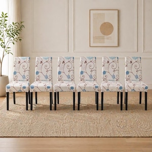 May include: Six dining chairs with black legs and cream-colored seats. The seats are patterned with a blue and brown floral design. The chairs are arranged in a row on a beige rug, with a neutral-toned wall and artwork in the background.