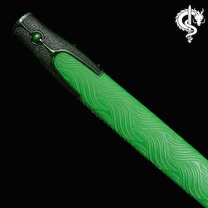 Pu&ograve; includere: Primo piano di un fodero per spada verde e nero. Il fodero presenta una superficie verde strutturata con un motivo a onde. L'elsa &egrave; nera con una gemma verde e accenti decorativi. Un logo di drago bianco si trova nell'angolo in alto a destra.