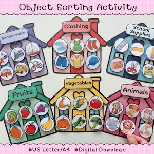 Puede incluir: Un juego de clasificación de objetos con seis tarjetas coloridas en forma de casa etiquetadas como Transportation, Clothing, School Supplies, Fruits, Vegetables y Animals. Cada casa incluye fichas circulares con ilustraciones.