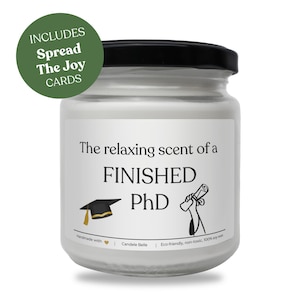 Könnte beinhalten: Ein weißes Kerzenglas mit schwarzem Deckel, beschriftet mit "The relaxing scent of a FINISHED PhD." Enthält eine Abschlusskappe und eine Diplomgrafik. Ein grüner Kreis liest "INCLUDES Spread The Joy CARDS."
