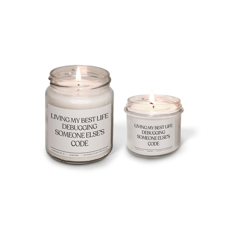 Peut inclure: Deux bougies en pot en verre transparent avec de la cire blanche et des m&egrave;ches allum&eacute;es. Chaque bougie porte une &eacute;tiquette blanche avec le texte noir : Living My Best Life Debugging Someone Else's Code. Les bougies sont de tailles diff&eacute;rentes.