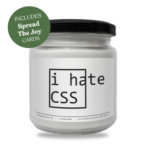 Peut inclure: Une bougie blanche dans un pot en verre transparent avec un couvercle noir. L'étiquette présente un cadre carré noir contenant le texte i hate CSS. Un badge circulaire vert dans le coin supérieur gauche affiche le texte INCLUDES Spread The Joy CARDS.