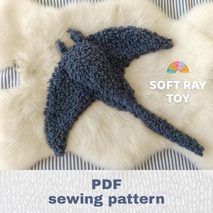 Peut inclure: Une peluche raie bleu foncé avec une surface texturée et bouclée. L'image comprend une icône arc-en-ciel colorée et le texte blanc "SOFT RAY TOY" ainsi que le texte "PDF sewing pattern" affiché dans une police bleu foncé en gras.